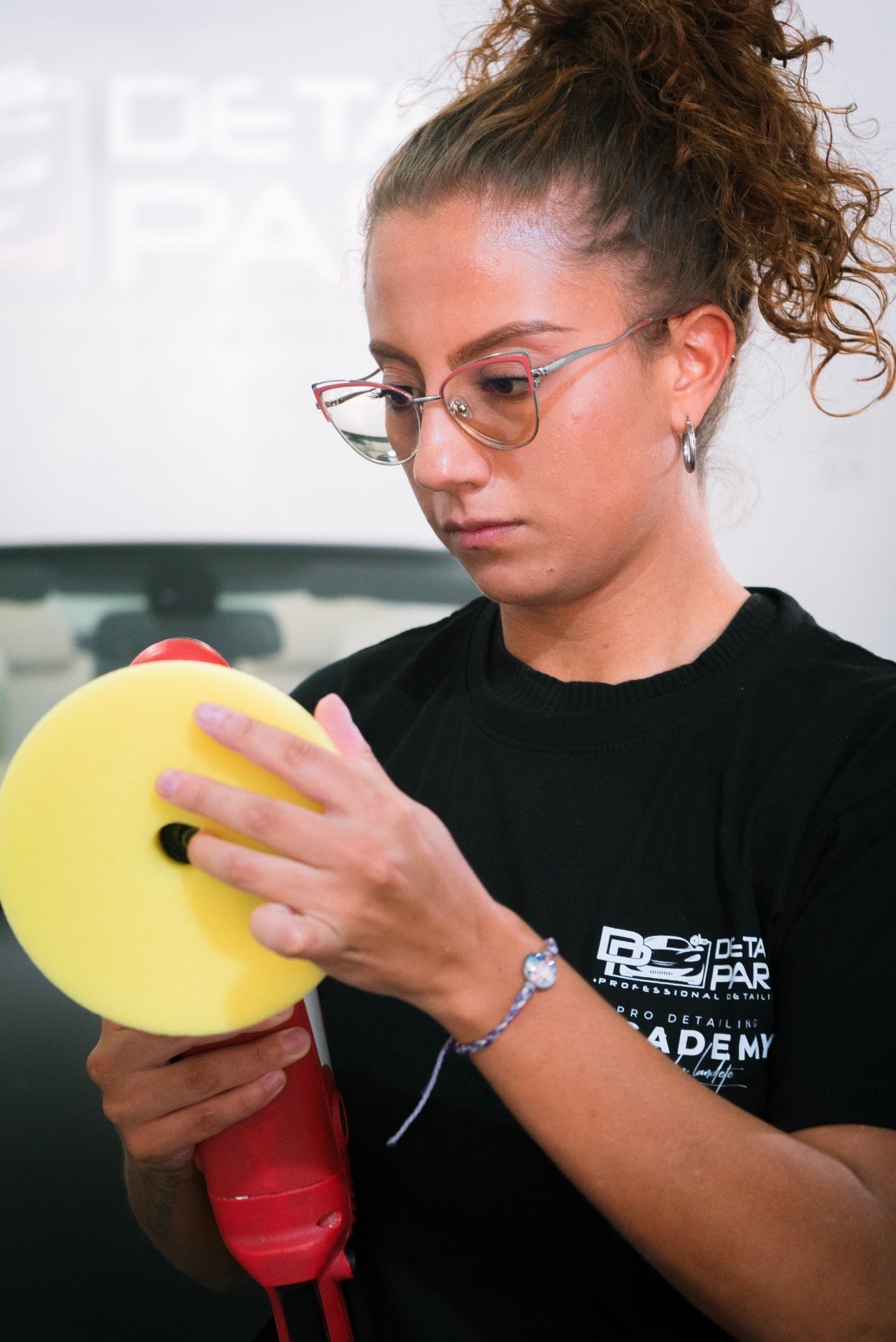 Alumna practicando con pulidora profesional en primer plano durante curso de detailing de Academia Detail