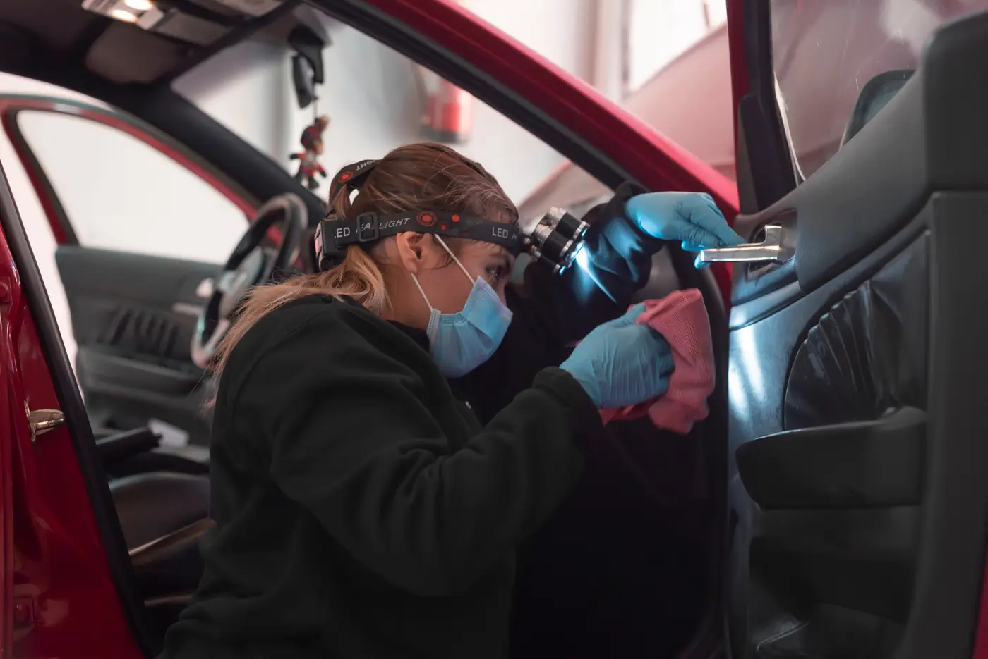 Alumna con frontal y mascarilla limpiando el interior de un coche