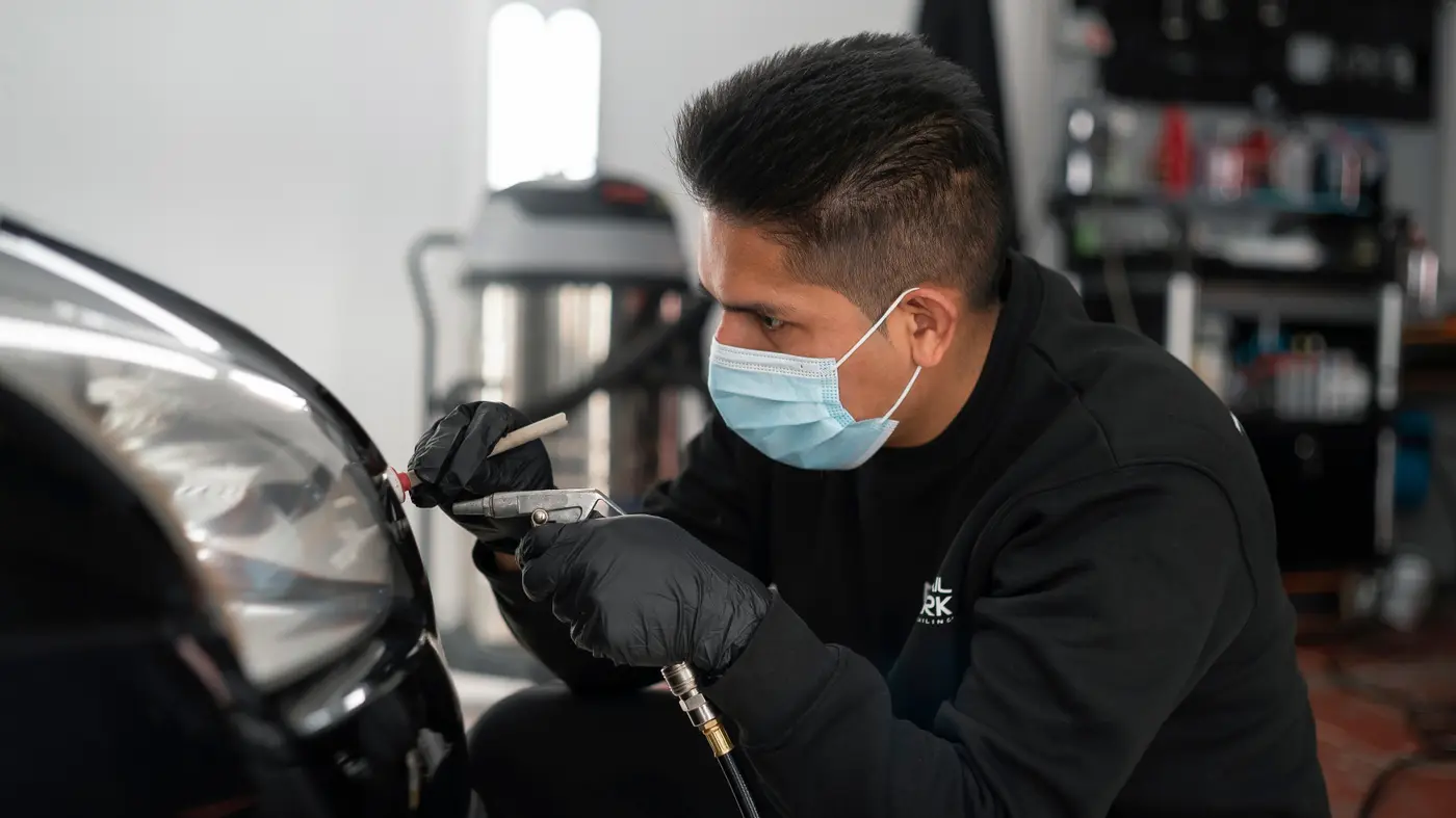 Técnico de Detail Park limpiando con aire a presión el contorno de un faro