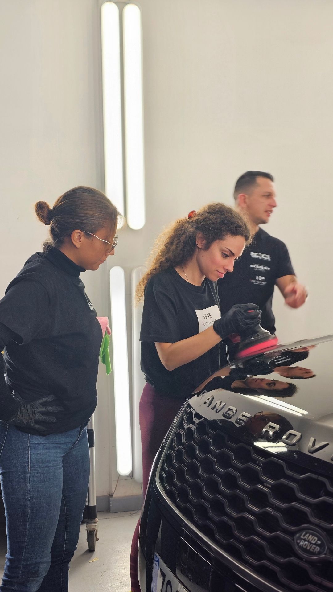 Alumnas practicando pulido profesional en Range Rover durante curso de detailing en Academia Detail