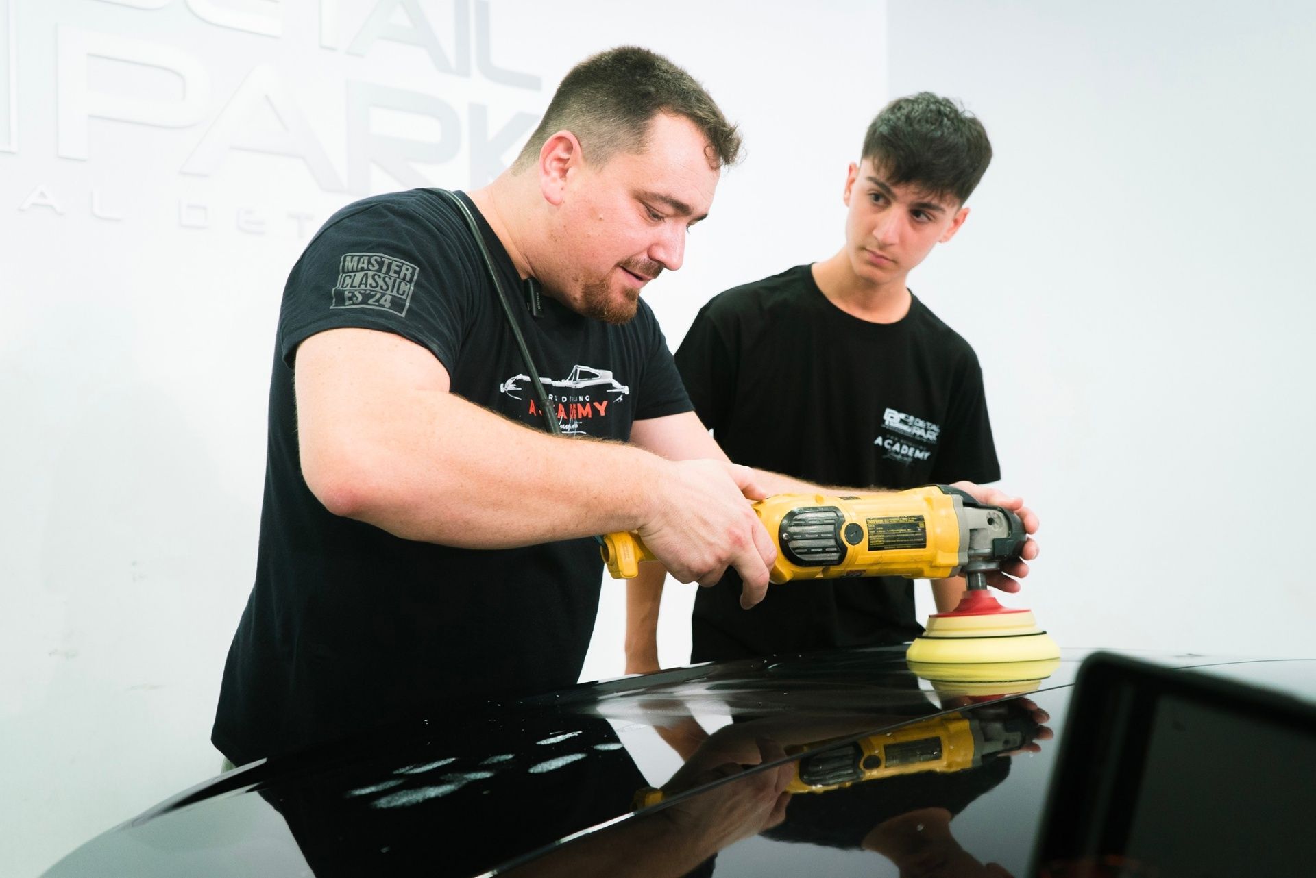 Instructor Leandro enseñando técnicas de pulido profesional a alumno en curso de detailing de Academia Detail